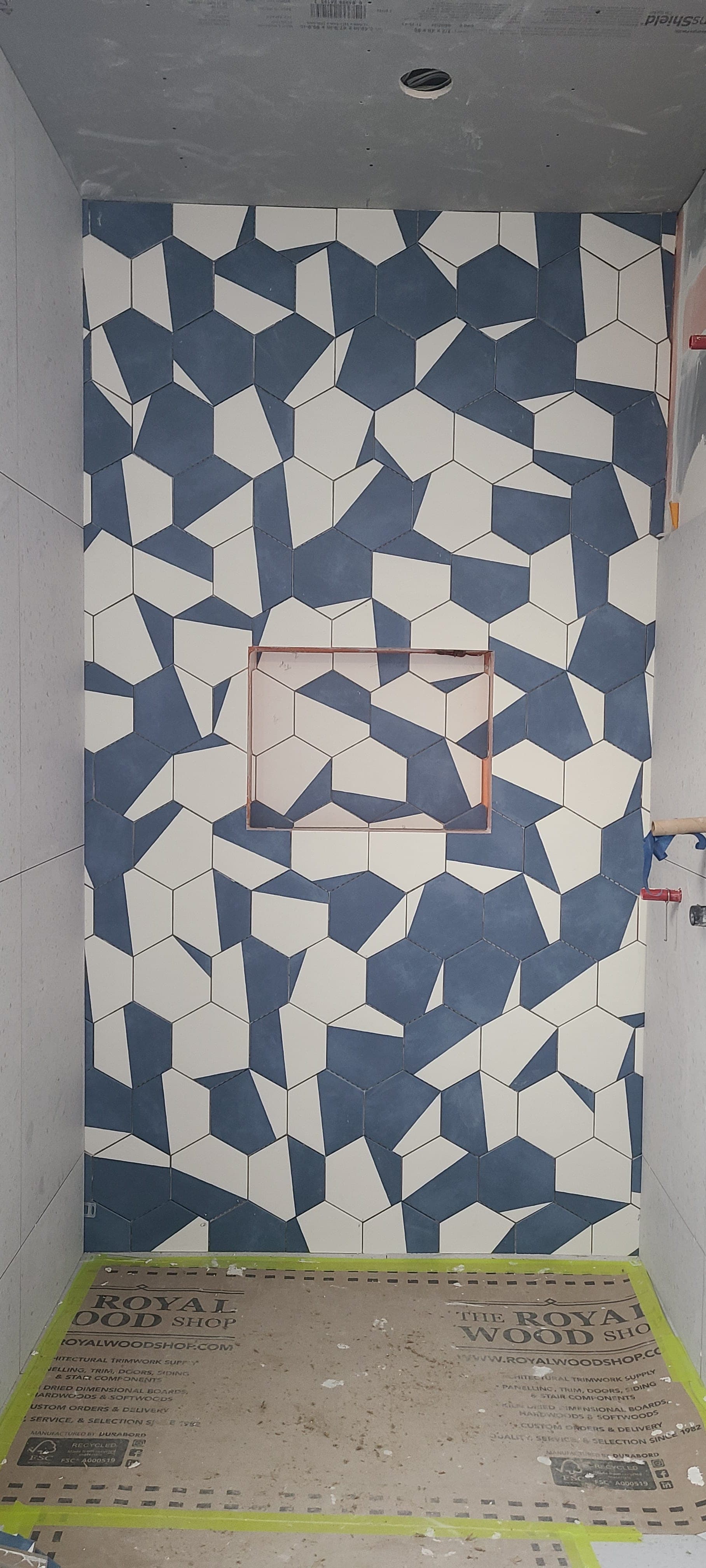 Detail view of custom blue and white hex mosaic with copper-framed niche template